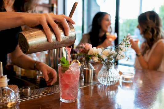 Hands pouring cocktail at cozy bar