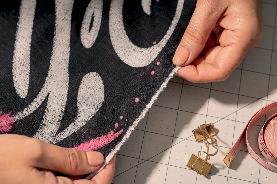 Hands inspecting printed garment fabric