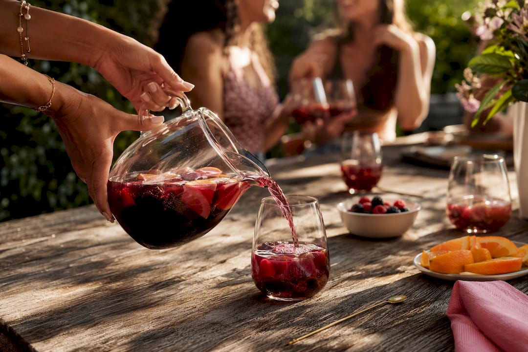 Friends pouring sangria at a patio gathering